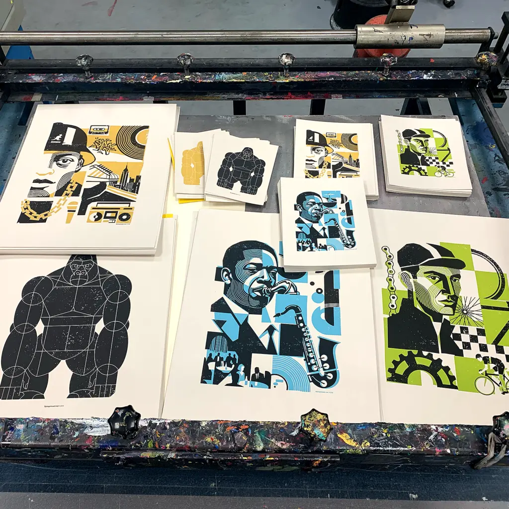 Foto of some fresh art prints by spiegelsaal.net The screenprinted art prints lay on a screenprint table.